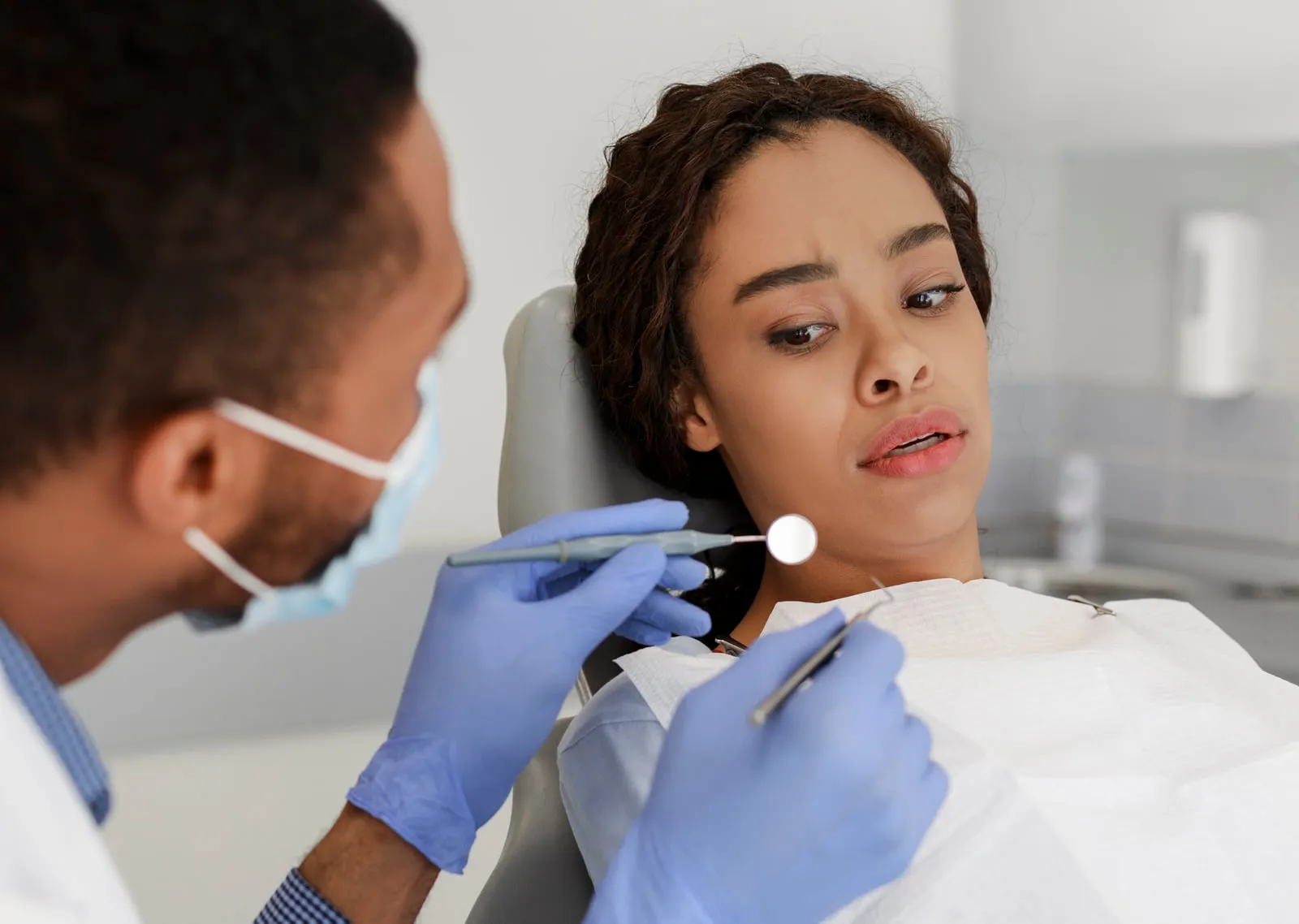 A dentist gently examining a patient in the dental chair