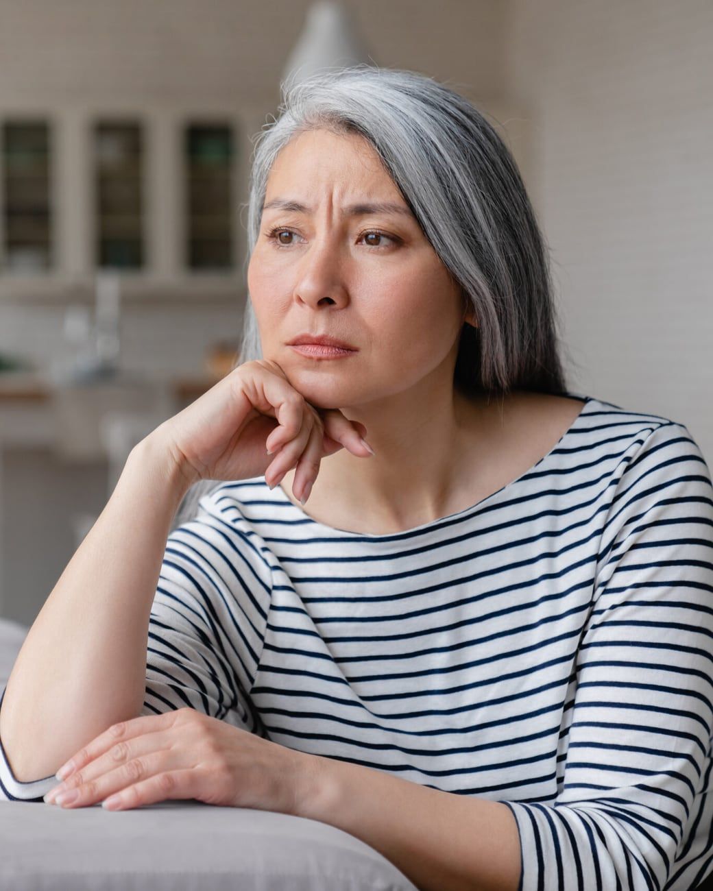 A woman sitting on a sofa at home, deep in thought